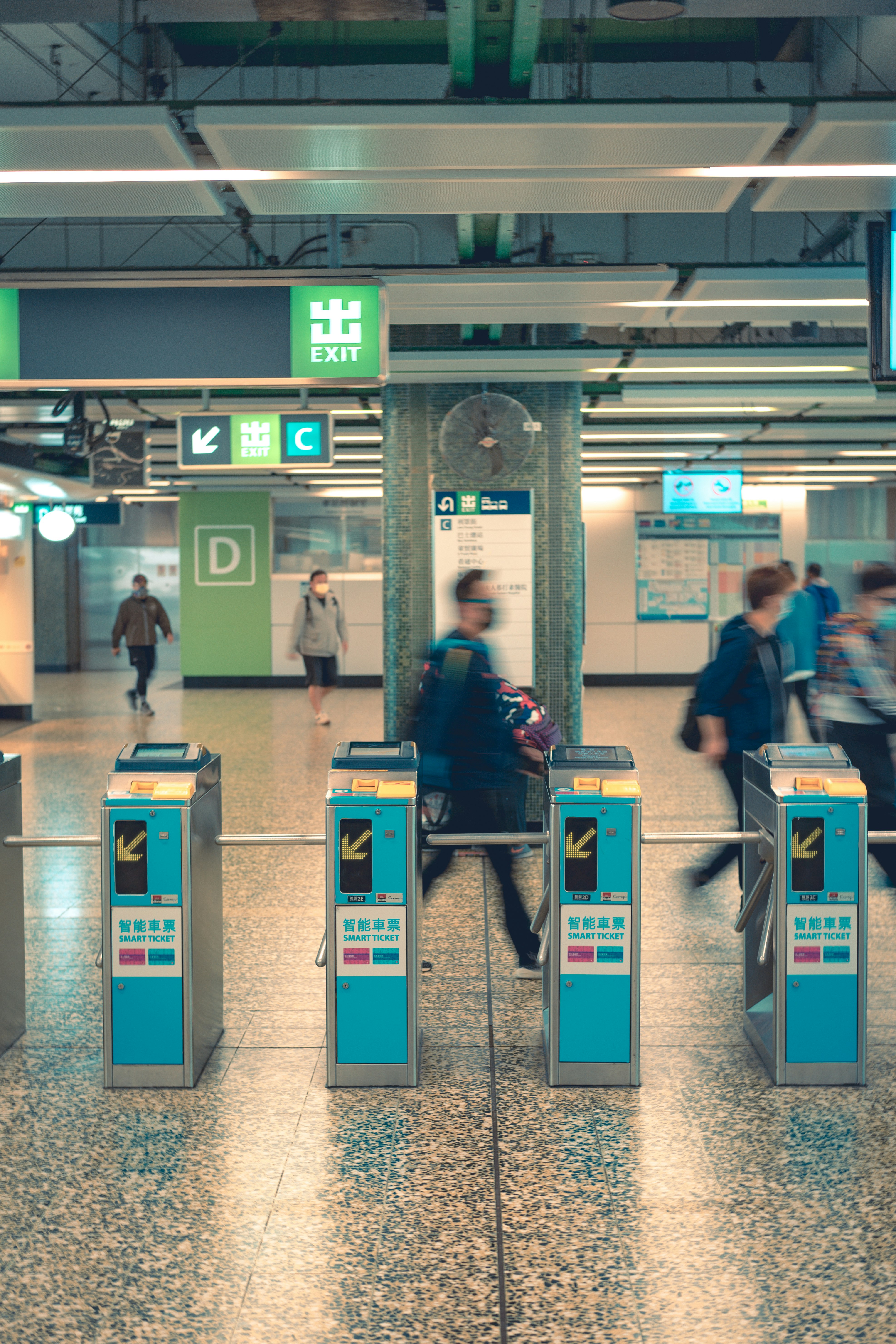 man in blue jacket standing near gray and green train station